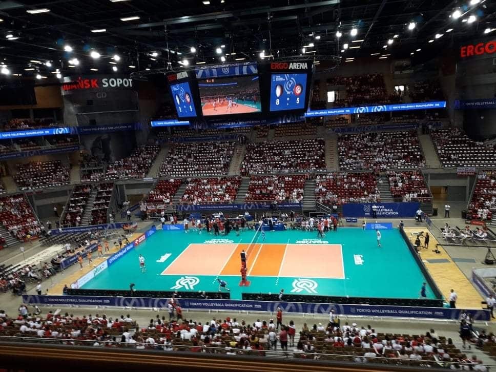 Mecz siatkówki w ERGO ARENIE w Gdańsku/Sopocie. Boisko do siatkówki na arenie z widocznym wynikiem meczu na telebimie i wypełnionymi trybunami.